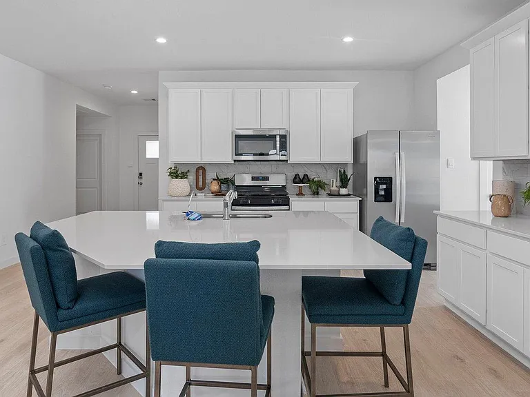Open-concept kitchen with a large waterfall island, ample cabinetry, and stainless steel appliances for everyday convenience.