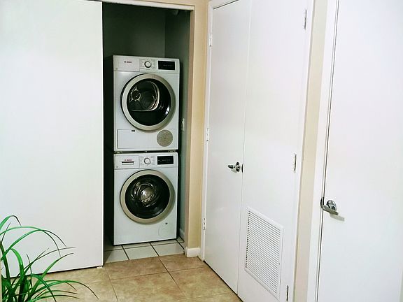 Entry room with laundry door open providing view of stacked washer and dryer.