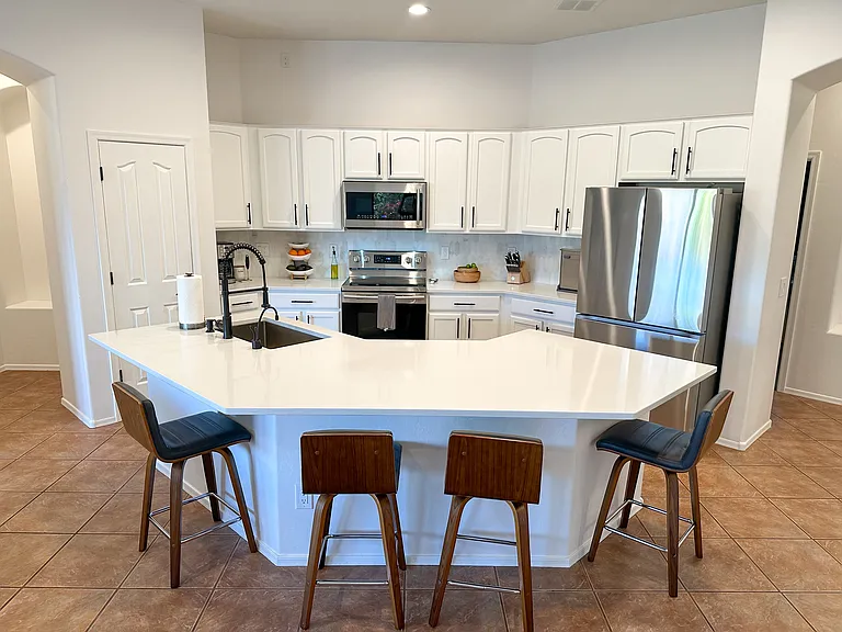 Upgraded kitchen with quartz countertops, stainless steel appliances, and newer fridge