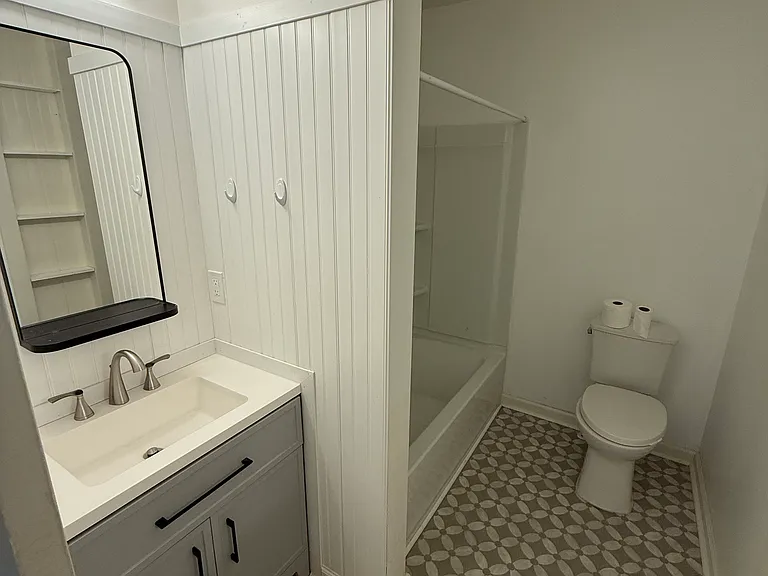 Bathroom with tub/shower and built in storage in the walls.