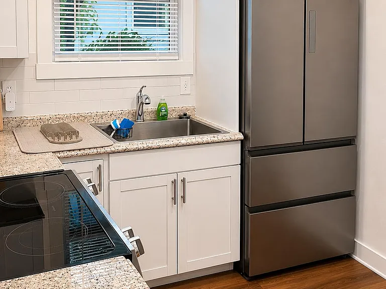 Well-equipped kitchen with shaker cabinets, granite-look counters, stainless sink, and full-size refrigerator with window lig