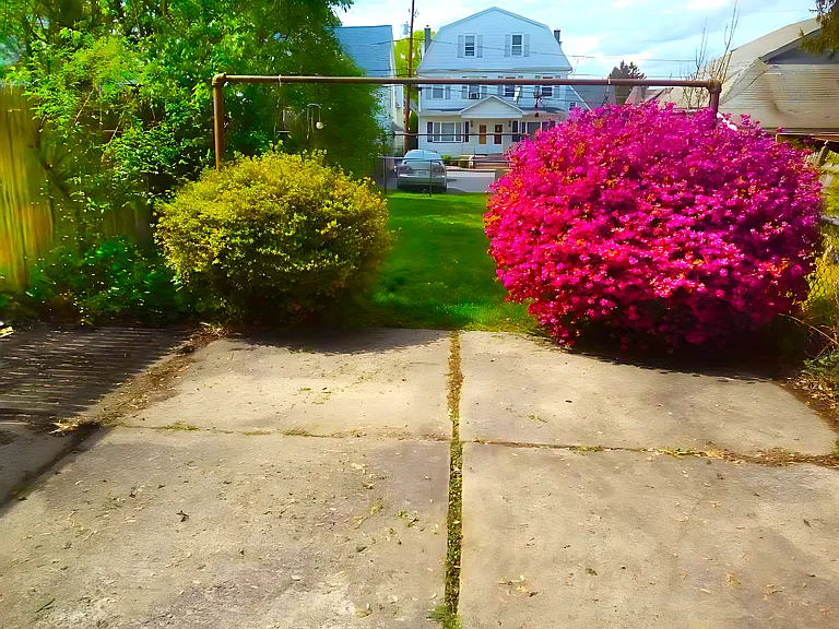 Rear concrete patio. The large, fully-fenced grass yard and your reserved spot in the paved parking lot are in the background. Behind the camera (not visible here) is the fully-enclosed rear porch.