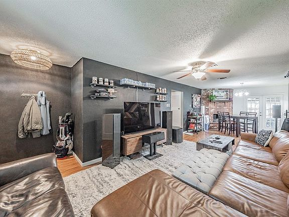 Living room with ceiling fan with notable chandelier, french doors, light wood-type flooring, and a textured ceiling