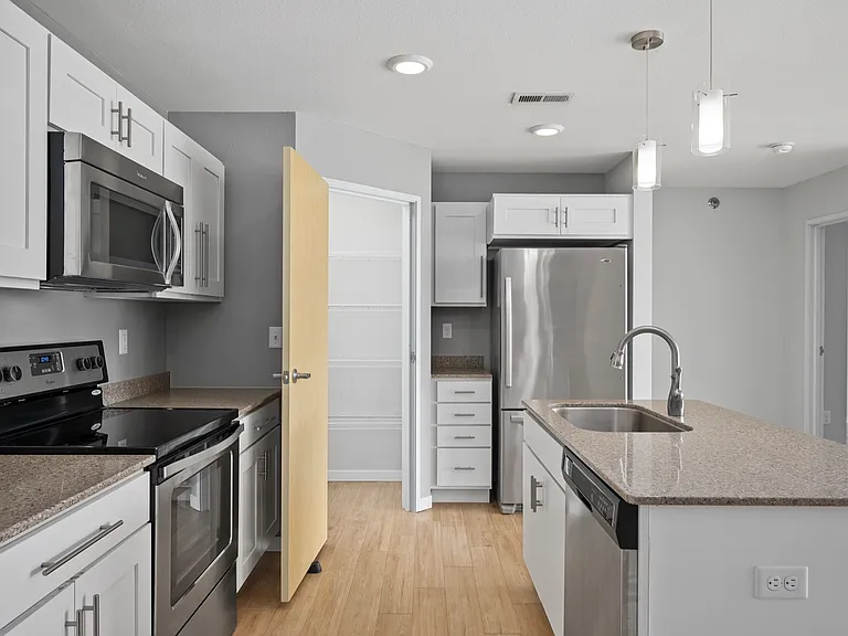 Modern kitchen with sleek stainless steel appliances, granite countertops, and elegant white cabinets, offering a spacious and inviting cooking area. Modern kitchen with sleek stainless steel appliances, granite countertops, and elegant white cabinets, of