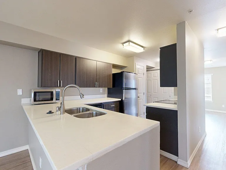 Apartment kitchen with stainless steel appliances, quartz countertops, and wood-style flooring.