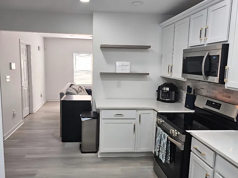 Updated kitchen with shaker cabinetry, quartz-style counters, open shelving, and stainless appliances for easy everyday cooki