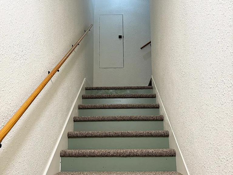 Stairway up to corner landing from POV of apartment's front door.