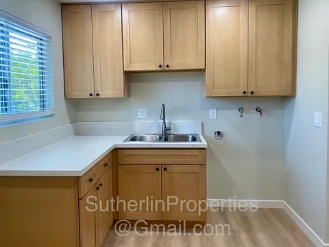 View of double stainless steel kitchen sink with pull down sprayer faucet, and the washer hook-up area