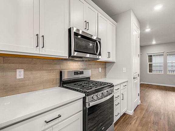 Detail of gourmet kitchen with quartz countertops, white cabinetry and stainless steel gas appliance