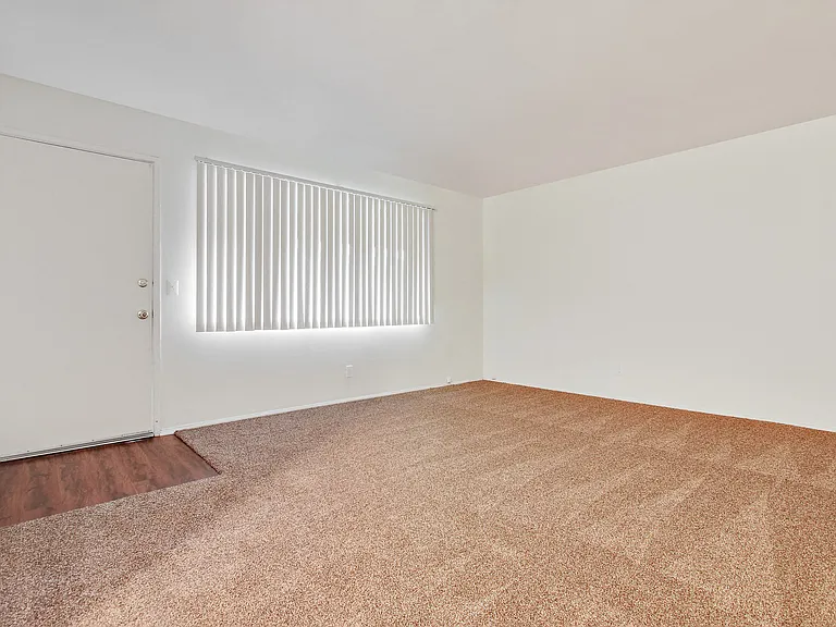 Living room with carpeted floors, wood style floors on the door entry area