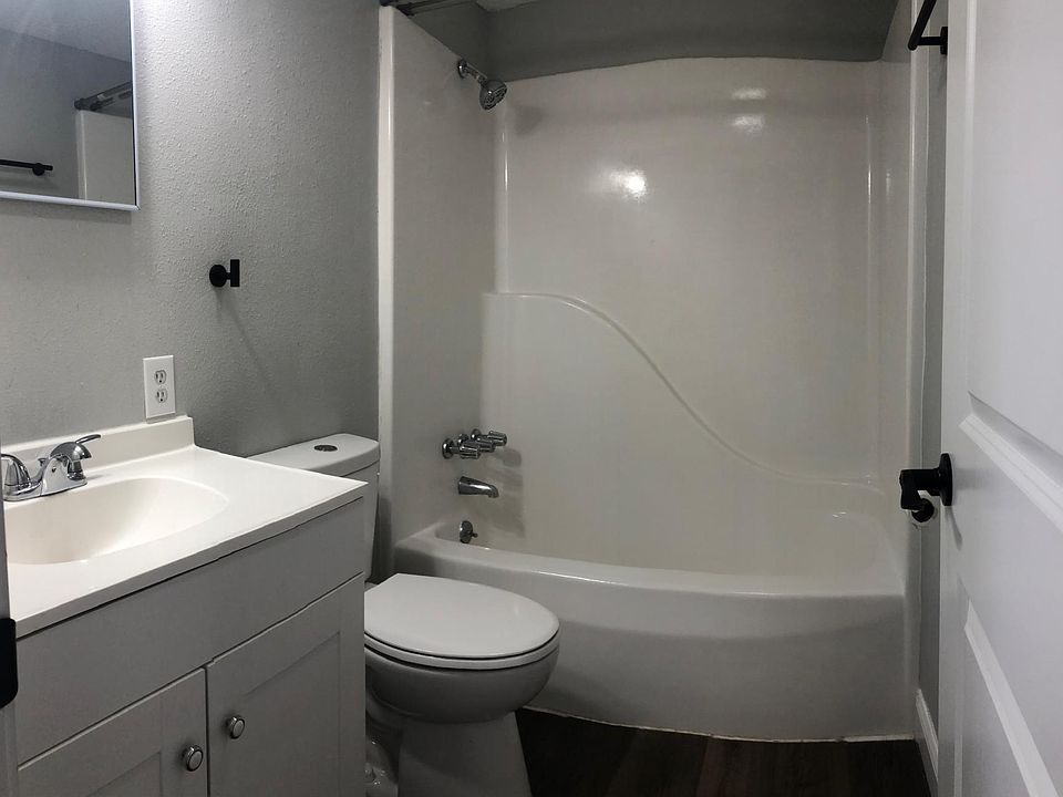 Bathroom with tub/shower combo, and framed mirror.