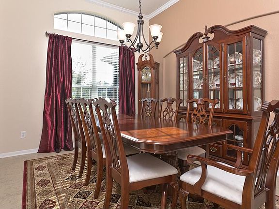 Dining room has crown molding and tile floors. This is a large dining room with lots of furniture - still spacious!