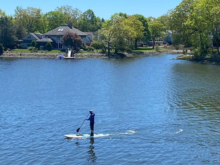 Paddleboarders and rowers cruise down the river.