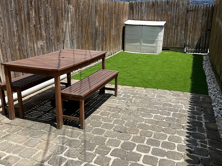 Backyard with stone patio, outdoor furniture, storage shed, and turf area