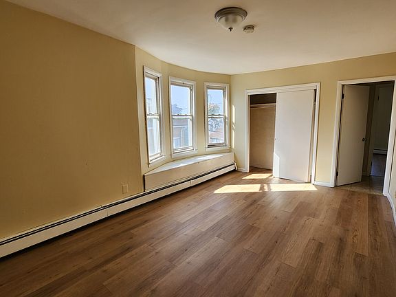 Another angle of the bedroom with bay window and full closet. New wood flooring.