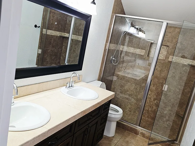 Primary bathroom featuring a dual-sink vanity and spacious walk-in shower, offering both comfort and functionality.