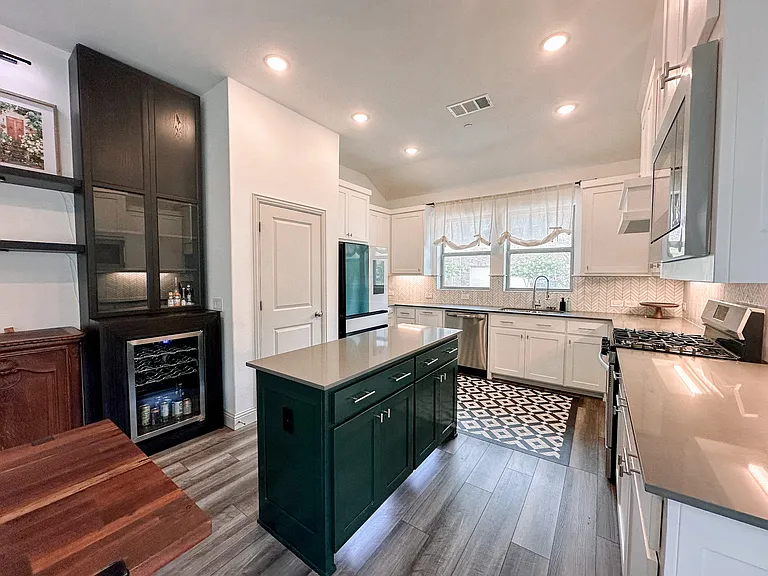Beautiful light and open kitchen with lots of counter space, statement island, gas cooking, and wine fridge and refrigerator included