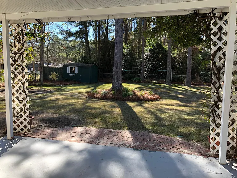View of large fenced-in backyard from covered patio