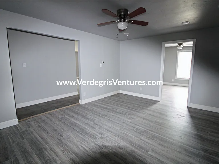 A spacious dining room sits at the very center of the home, serving as a natural hub between the kitchen and bedrooms. It features a ceiling fan and also functions as a convenient hallway connecting the main living areas