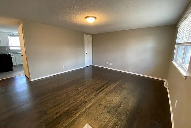 Large living area featuring hardwood flooring, neutral paint, and abundant natural light.