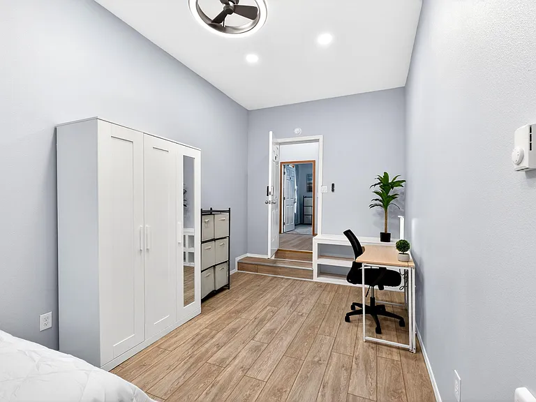 Private bedroom with wood-style flooring, wardrobe storage, and a dedicated desk area for studying or working from home.