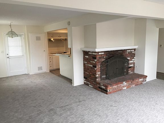 Dining room to left, standing in living room, fireplace and kitchen area.