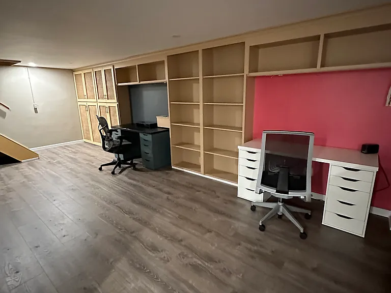 Refinished basement with built-in shelving and two desk areas.