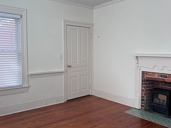 Interior view of front bedroom showing decorative fireplace with ceramic tile hearth and electric 'fireplace' insert (will be left with unit unless occupant does not want it). Door to bathroom.