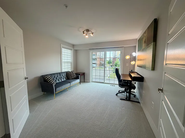 Electric stand up desk and sofa bed in bright airy second floor room with balcony.