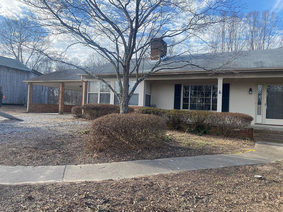 Exterior front of house with 2 car carport, sunroom, covered front porch.