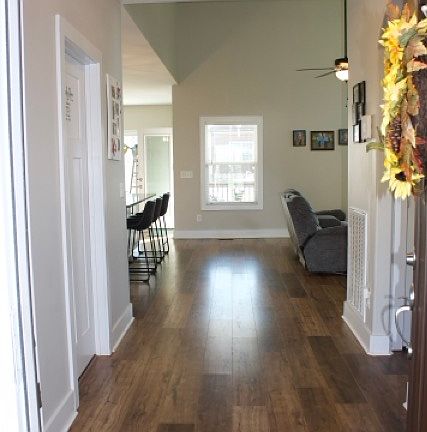 Front Entryway. Laundry Room on the left and downstairs bathroom and bedroom on the right. Main living room straight ahead. Large island, kitchen and dining table to the left.