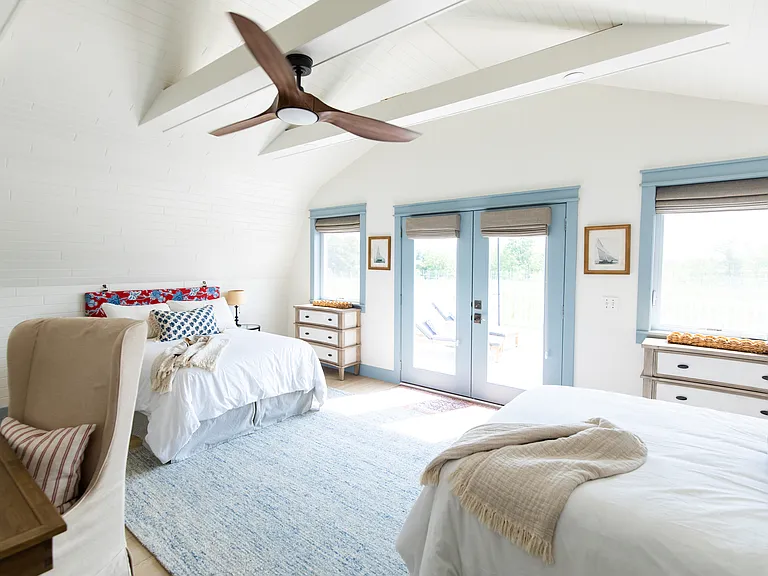 The second bedroom includes two full beds, two small dressers, a closet, a desk, and French doors that open out to the expansive back deck that overlooks vineyards.