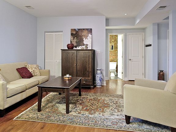 living room, utility closet, stackable washer/dryer in closet, exposed brick in bathroom, linen closet