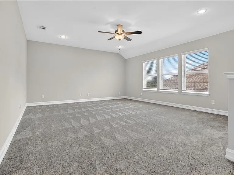 Spacious interior room featuring a vaulted ceiling with recessed lighting and a ceiling fan