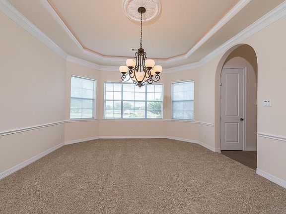 Dining room features include a tray ceiling with rope lighting, double crown molding, chair railing, a decorative chandelier and a door to the kitchen for ease in serving dining guests plus beautiful lake views!