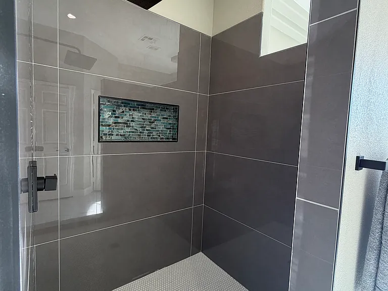 Spacious walk-in shower with rainfall head and custom tile niche