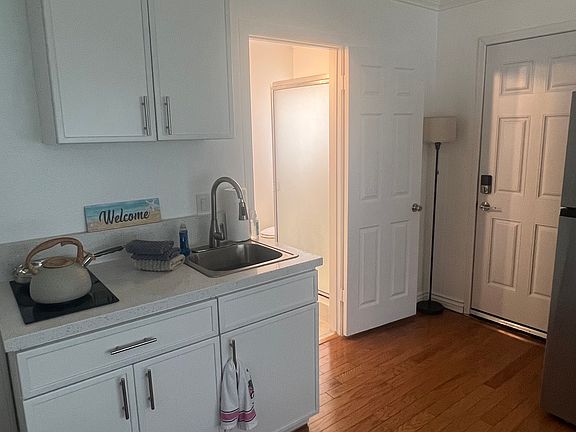 Kitchenette w/ cooktop stove, sink w/ garbage disposal, and cabinet