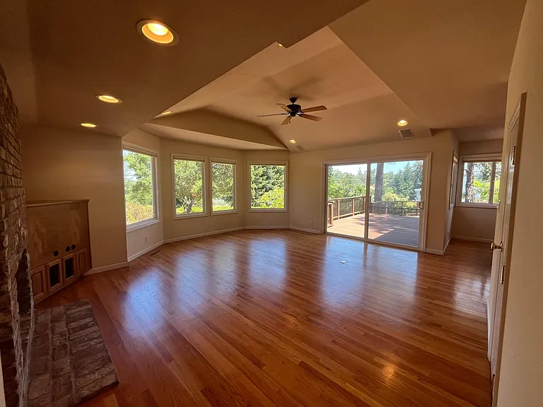 Grand family room features built-in cabinetry, vaulted ceiling, hardwood flooring, bay windows and a patio door that leads to a huge inviting outdoor deck beckoning for entertainment or relaxation.