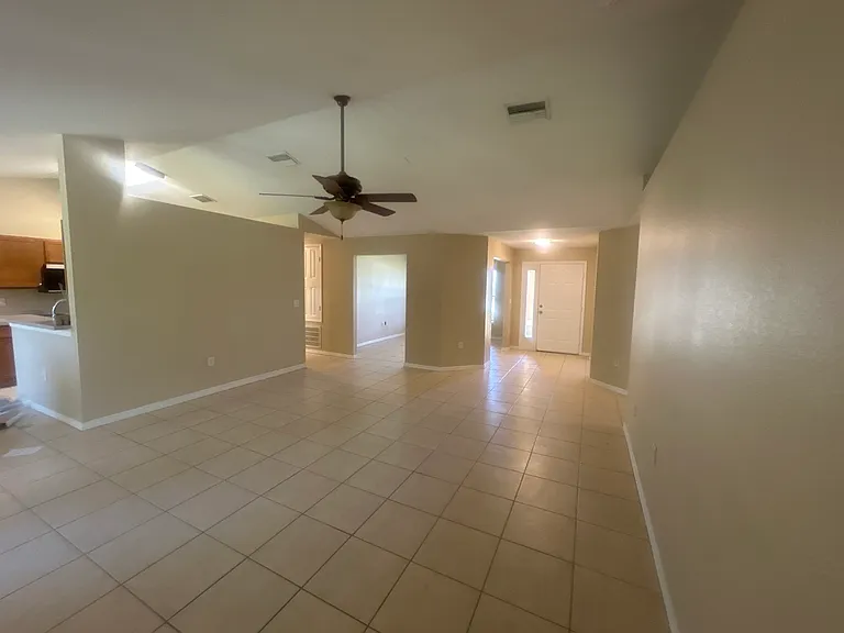 Living room with view of front door, 2 open bonus rooms and kitchen
