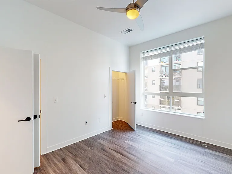 Spacious apartment bedroom with large closet and wood-style flooring.