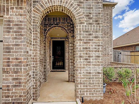 Guests will enter this elegant home through a covered brick courtyard entry surrounded by mature landscaping.