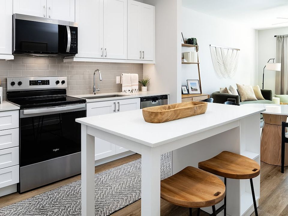 Finish Package I kitchen with stainless steel appliances, white cabinetry, grey tile backsplash, white quartz countertops, and hard surface flooring