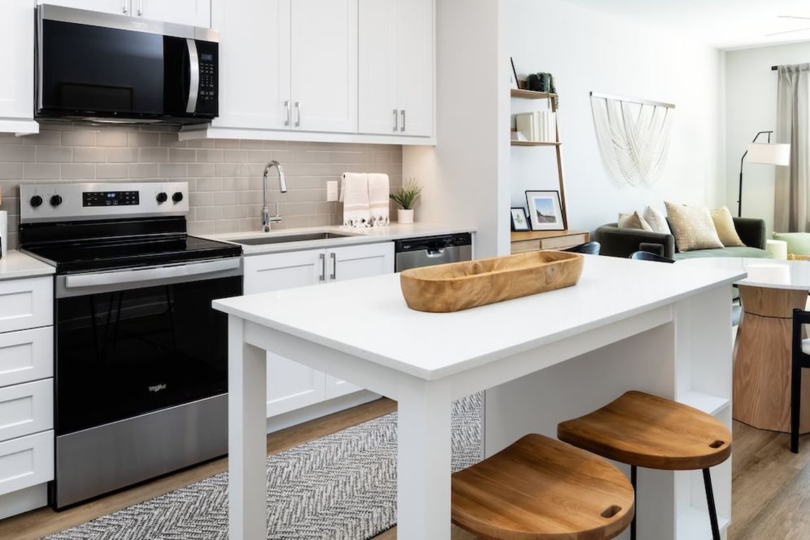 Finish Package I kitchen with stainless steel appliances, white cabinetry, grey tile backsplash, white quartz countertops, and hard surface flooring