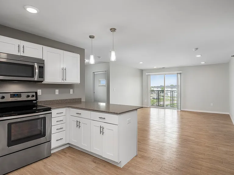 Modern open-concept kitchen and living area with stainless steel appliances and natural light from large sliding glass doors. Modern open-concept kitchen and living area with stainless steel appliances and natural light from large sliding glass doors.