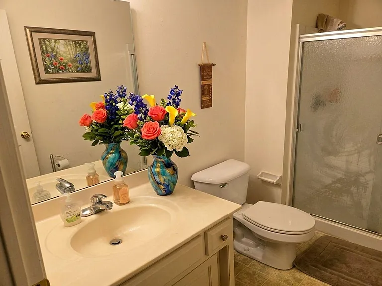 Private, full bathroom with vanity sink, large mirror, and shower with sliding glass doors for easy upkeep.