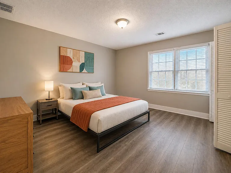 Spacious bedroom with wood-style flooring, large window with blinds, and a closet for convenient everyday storage.