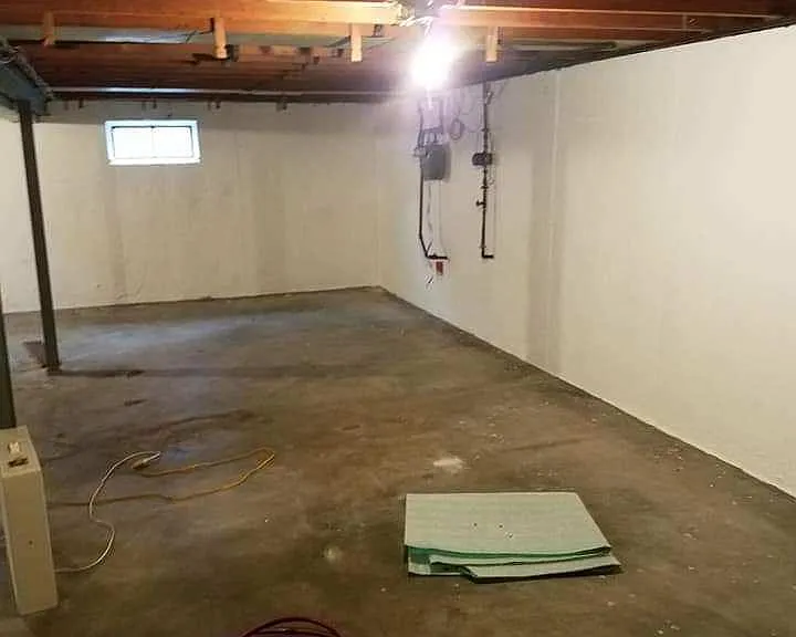 Freshly painted basement. Walls are painted white and the floor is painted light gray.