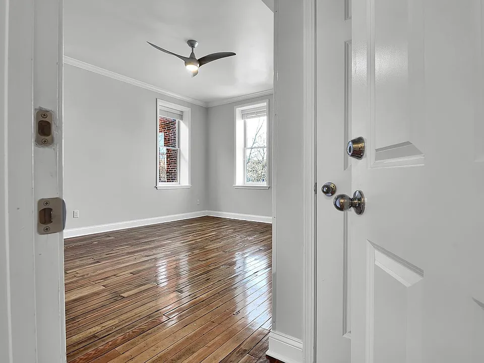looking in from the front door to the unit, beautifully salvaged wood floors, contemporary fan
