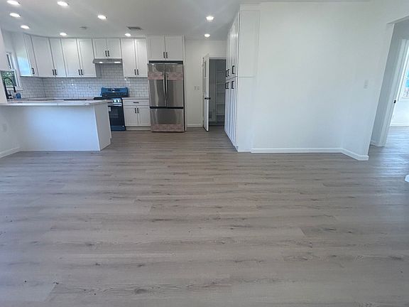 New kitchen cabinets, counter, backsplash, sink, peninsula, and appliances (POV from living room)