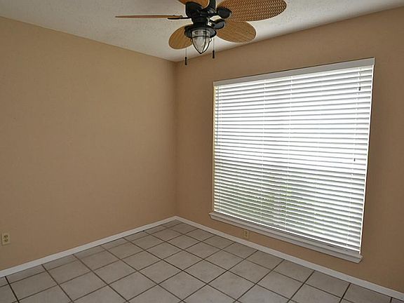 Bedroom or study offering tile flooring, ceiling fan with light fixture, two inch window blinds and nice closet space.